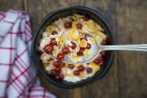 Yogurt with cornflakes and red currants on spoon and in bowl — Stock Photo
