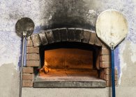 Aufgehellter Pizzaofen und Schalen in der Nähe platziert — Stockfoto