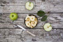 Schüssel mit Apfelchips, Blättern, Küchenmesser und zwei Oma-Schmied auf Holz — Stockfoto