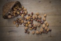Wickerbasket, walnuts, almonds and hazelnuts on wood — Stock Photo