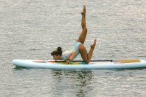 Woman practicing paddle board yoga — Stock Photo