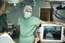 Portrait du chirurgien en salle d'opération penché sur la machine d'anesthésie — Photo de stock