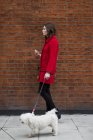 Young woman wearing red jacket going walkies with her dog — Stock Photo