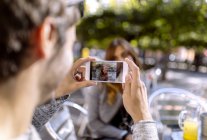 Junger Mann fotografiert Freundin mit Smartphone — Stockfoto