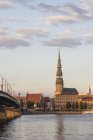 Letônia, Riga, vista através do Daugava à igreja de São Pedro na luz do pôr-do-sol — Fotografia de Stock