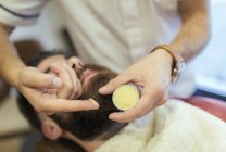 Barber applying cream on beard of a customer — Stock Photo