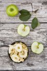 Schüssel mit Apfelchips, Blättern und ganzen und in Scheiben geschnittenen Omas Schmied auf Holz — Stockfoto