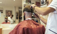 Парикмахерская бреет голову клиента в парикмахерской — стоковое фото