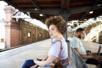 Молодая женщина сидит на скамейке на вокзале — стоковое фото