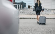Vue arrière de la femme d'affaires avec valise en mouvement — Photo de stock