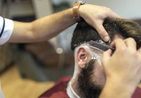 Крупный план парикмахерской бреющей бороды клиента — стоковое фото