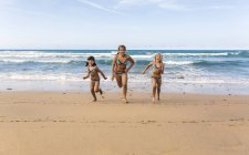 Espanha, Colunga, três meninas correndo lado a lado na praia — Fotografia de Stock