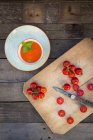 Cuenco de sopa de crema de tomate y tabla de cortar con tomates enteros y en rodajas - foto de stock
