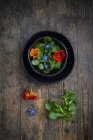 Bowl of salad with lettuce, blossoms of borage and Indian cress — Stock Photo