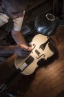 Geigenbauer untersucht den Soundpfosten einer ungeschminkten Geige in seiner Werkstatt — Stockfoto