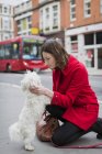 Royaume-Uni, Londres, jeune femme agenouillée sur le trottoir face à son chien — Photo de stock