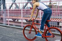 USA, New York City, Williamsburg,  woman riding red racing cycle on Williamsburg Bridge — Stock Photo