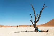 Намібія, Наміб, людина відпочиває на Мертве дерево у Deadvlei — стокове фото