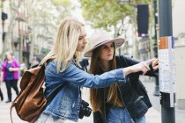 España, Barcelona, dos mujeres jóvenes mirando el mapa de la ciudad en el polo - foto de stock