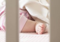 Cropped view of baby foot with blanket in cot — Stock Photo