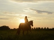 Junge Frau reitet in den Sonnenuntergang — Stockfoto