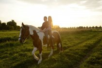 Junge Frauen reiten bei Sonnenuntergang auf einem Feld — Stockfoto