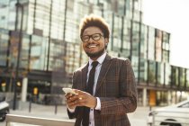 Sorrindo jovem empresário ao ar livre com telefone celular — Fotografia de Stock