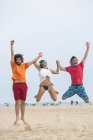 Spagna, Cadice, El Puerto de Santa Maria, Amici che saltano sulla spiaggia — Foto stock