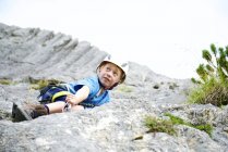 Vista de ángulo bajo de niño pequeño escalando la roca - foto de stock