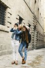 Spain, Barcelona, two young women walking in city with camera — Stock Photo