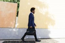 Giovane uomo d'affari con valigetta che cammina sul marciapiede — Foto stock