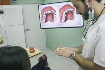 Стоматолог мужского пола разговаривает с пациентом в клинике — стоковое фото