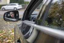 Reflexão do jovem no espelho do carro — Fotografia de Stock