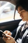 Бізнесмен на задньому сидінні автомобіля, за допомогою мобільного телефону — стокове фото