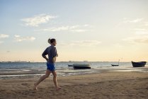 Іспанія, Пуерто-Реаль, жінка, біг на пляжі в вечірні сутінки — стокове фото