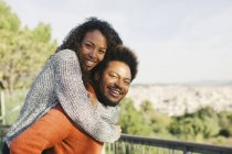 Retrato de un joven feliz dando a su novia un paseo a cuestas - foto de stock