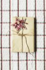 Завернутый рождественский подарок на проверенной ткани — стоковое фото