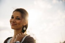 Porträt einer lächelnden jungen Frau im Gegenlicht — Stockfoto