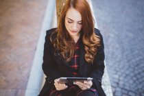 Молода жінка дивиться на цифровий планшет на відкритому повітрі — стокове фото