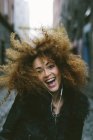 Portrait de femme heureuse avec des cheveux afro musique auditive avec écouteurs — Photo de stock