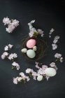 Easter nest with eggs, silver Easter bunny, feathers and cherry blossoms — Stock Photo