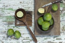 Whole and sliced limes and kitchen knife on wood — Stock Photo