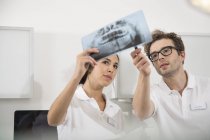 Dos dentistas en cirugía dental discutiendo imagen de rayos X - foto de stock