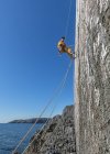 Man climbing on rock at Mother Carey 's Kitchen, Pembroke, Reino Unido — Fotografia de Stock