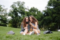 Two happy friends in a park looking at cell phone — Stock Photo