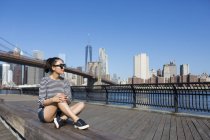USA, New York City, relaxing young woman sitting outdoors with city view — Stock Photo