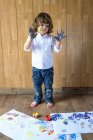 Retrato de menino criativo com palmas cheias de cores de dedo — Fotografia de Stock