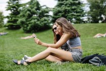 Два счастливых друга в парке смотрят на сотовый телефон — стоковое фото