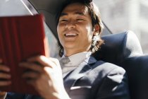 Усміхаючись бізнесмен на задньому сидінні автомобіля, використовуючи цифровий планшетний — стокове фото