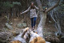Giovane donna che attraversa un ponte fatto di tronchi d'albero — Foto stock